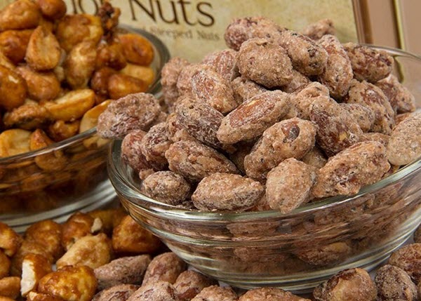 Two bowls of nuts against a tin. 