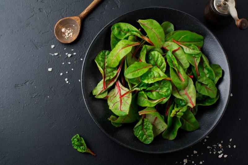 A black bowl with fresh beet greens