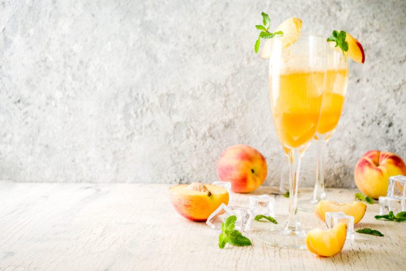 Two champagne glasses containing a Bellini cocktail