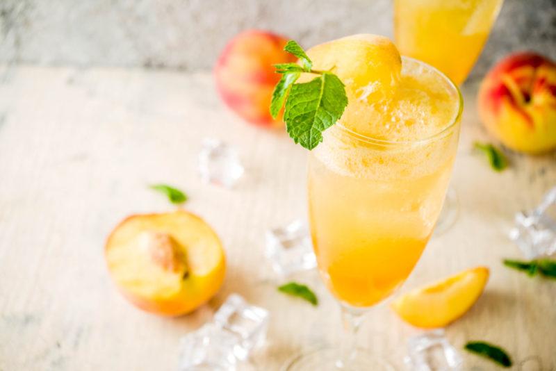 A peach bellini with ice and peaches on a table