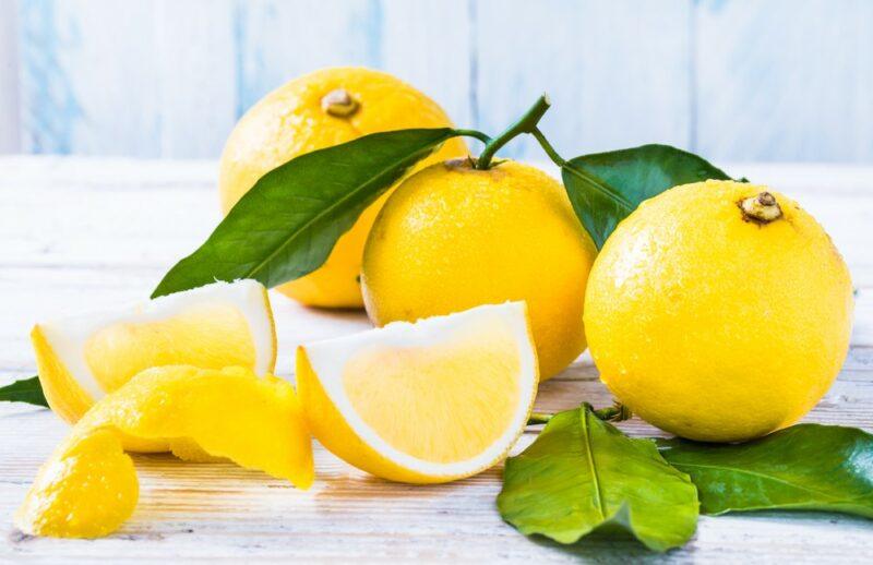 Bright yellow bergamot oranges on a white table with their leaves