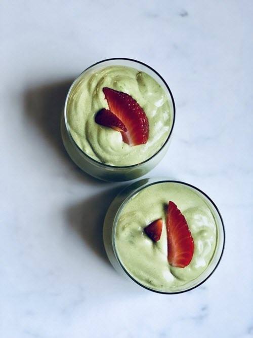 Top down image of two glasses that are filled with a light green smoothie