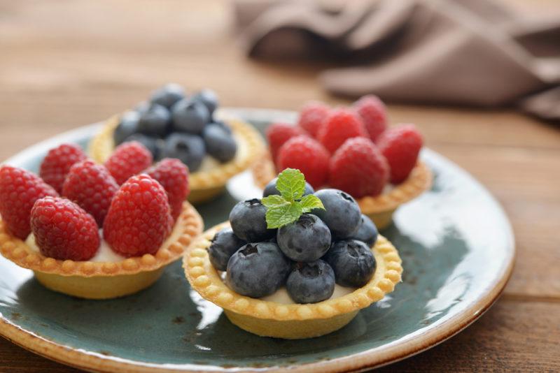 Four small fruit tarts, two with raspberries, two with blueberries