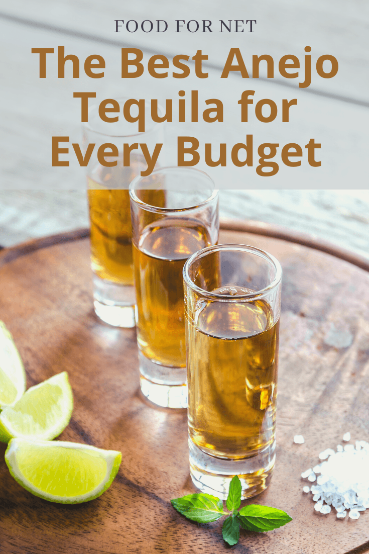 Three shot glasses of anejo tequila on a wooden table