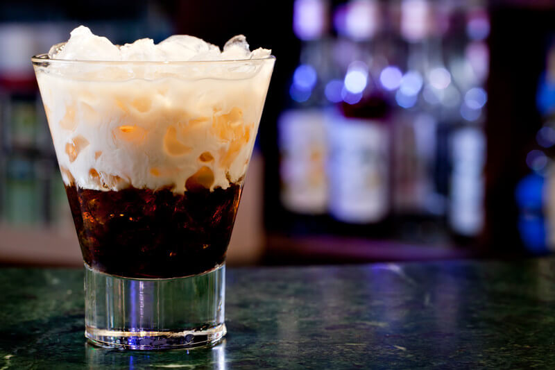 white Russian cocktail with a dimly lit bar in the background