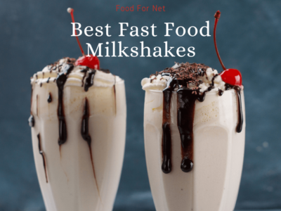 Two vanilla milkshakes in glasses with chocolate syrup and glace cherries