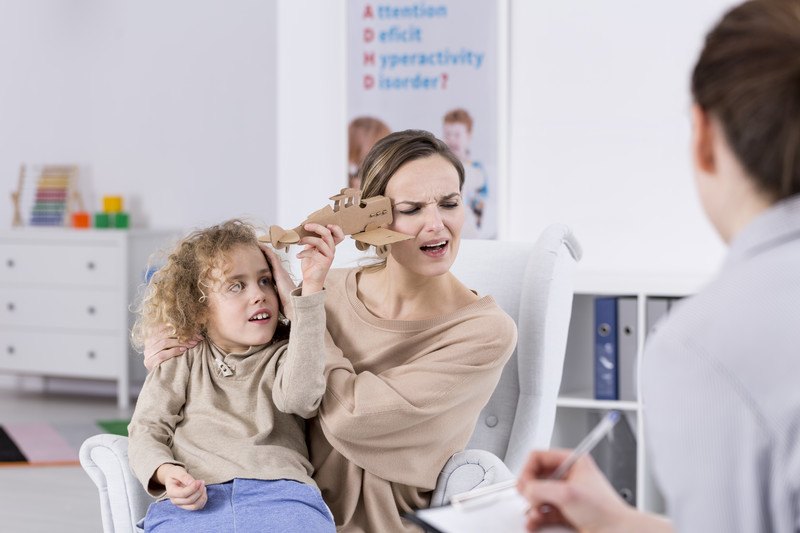 An annoyed woman sits with her ADHD child during a visit with a psychologist, representing the best foods for ADHD.
