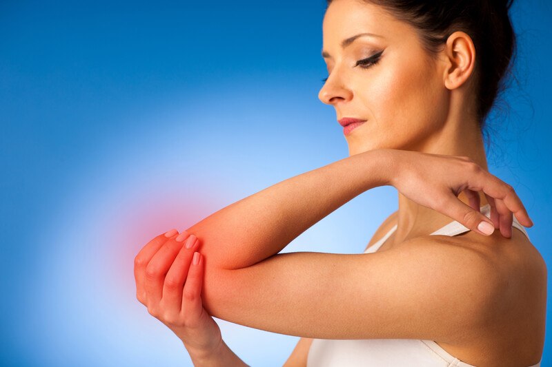 Best Foods Autoimmune Disease | Food For Net A dark-haired woman in a white tank top holds her elbow, which glows red, with her opposite hand, representing the best foods for autoimmune disease.
