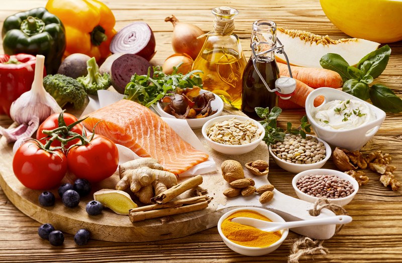 This photo shows several types of heart-healthy foods, including salmon, turmeric, beans, yogurt, and more, representing the best foods for the heart and arteries.