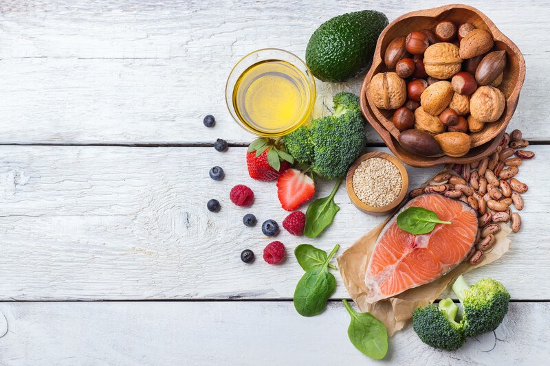 Best Foods Heart Health | Food For Net This photo shows an overhead view of olive oil, berries, spinach, nuts, salmon, broccoli, and beans, representing the best foods for heart health.