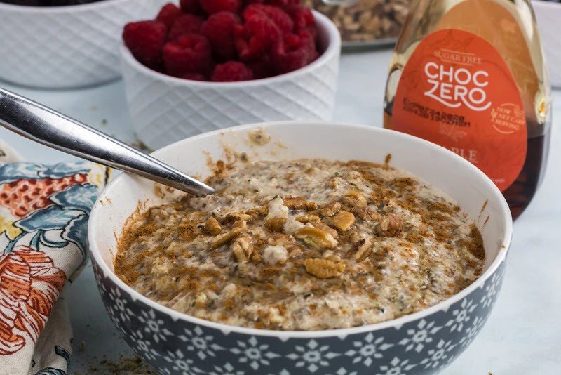 A bowl of keto oatmeal with toppings in the background