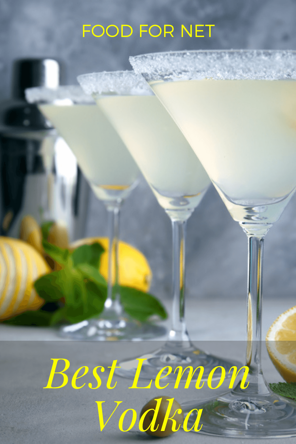 data-fastload Three glasses of a lemon drop cocktail made with lemon vodka, in front of a vodka bottle on the back wall