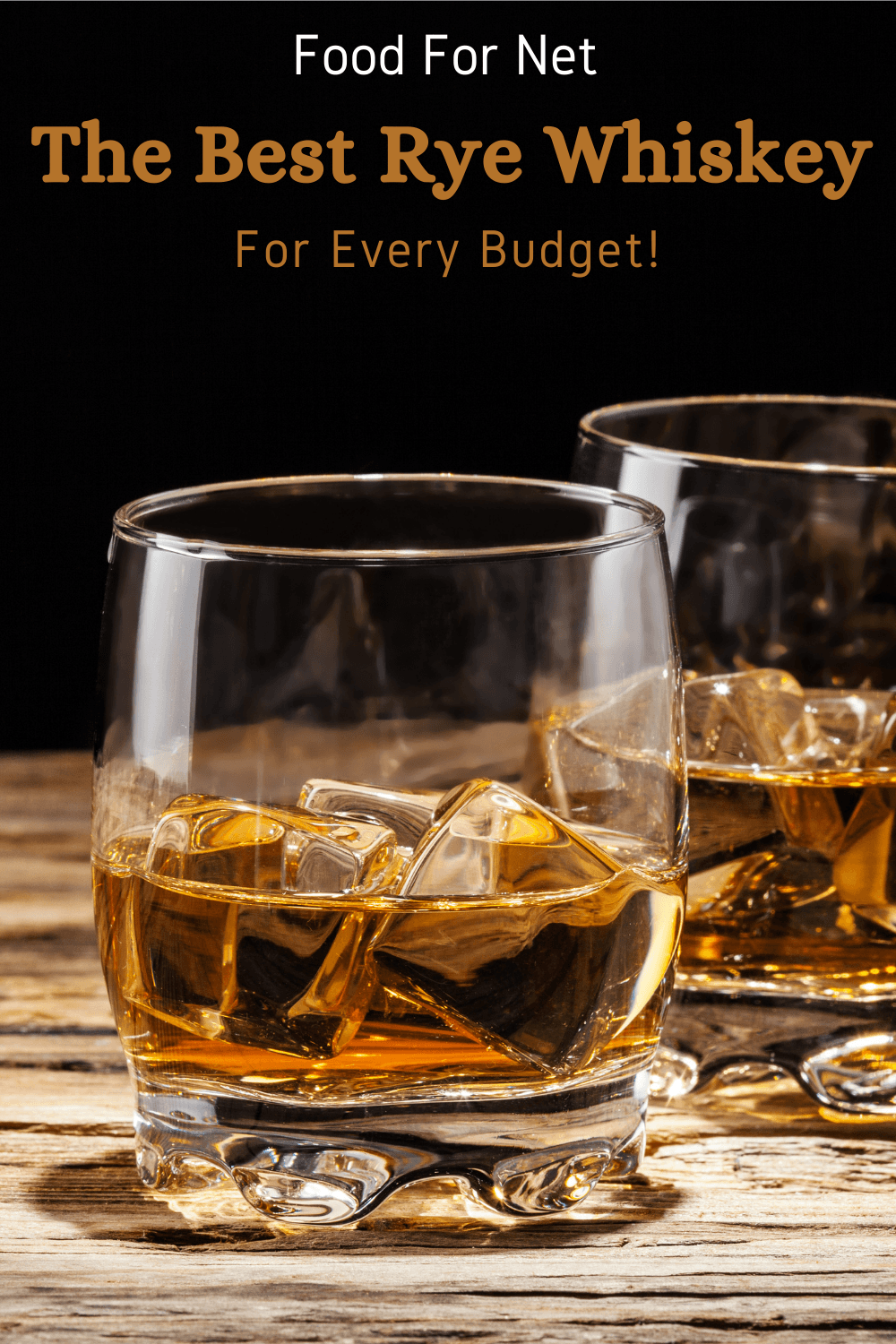 Two glasses of rye whiskey with ice on a wooden table against a black background