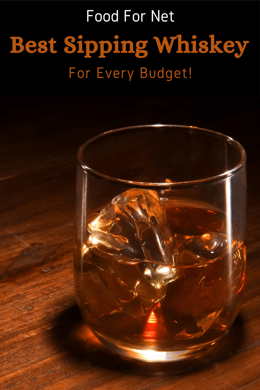 A glass of whiskey on the rocks on a wooden table against a black background