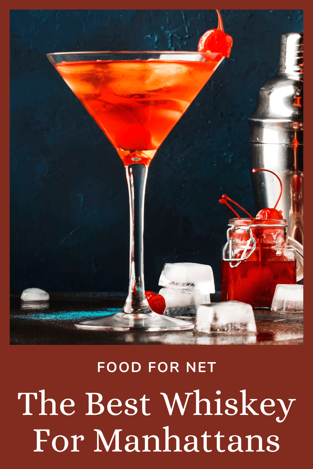 A Manhattan cocktail on a table next to ice, cherries and a cocktail shaker