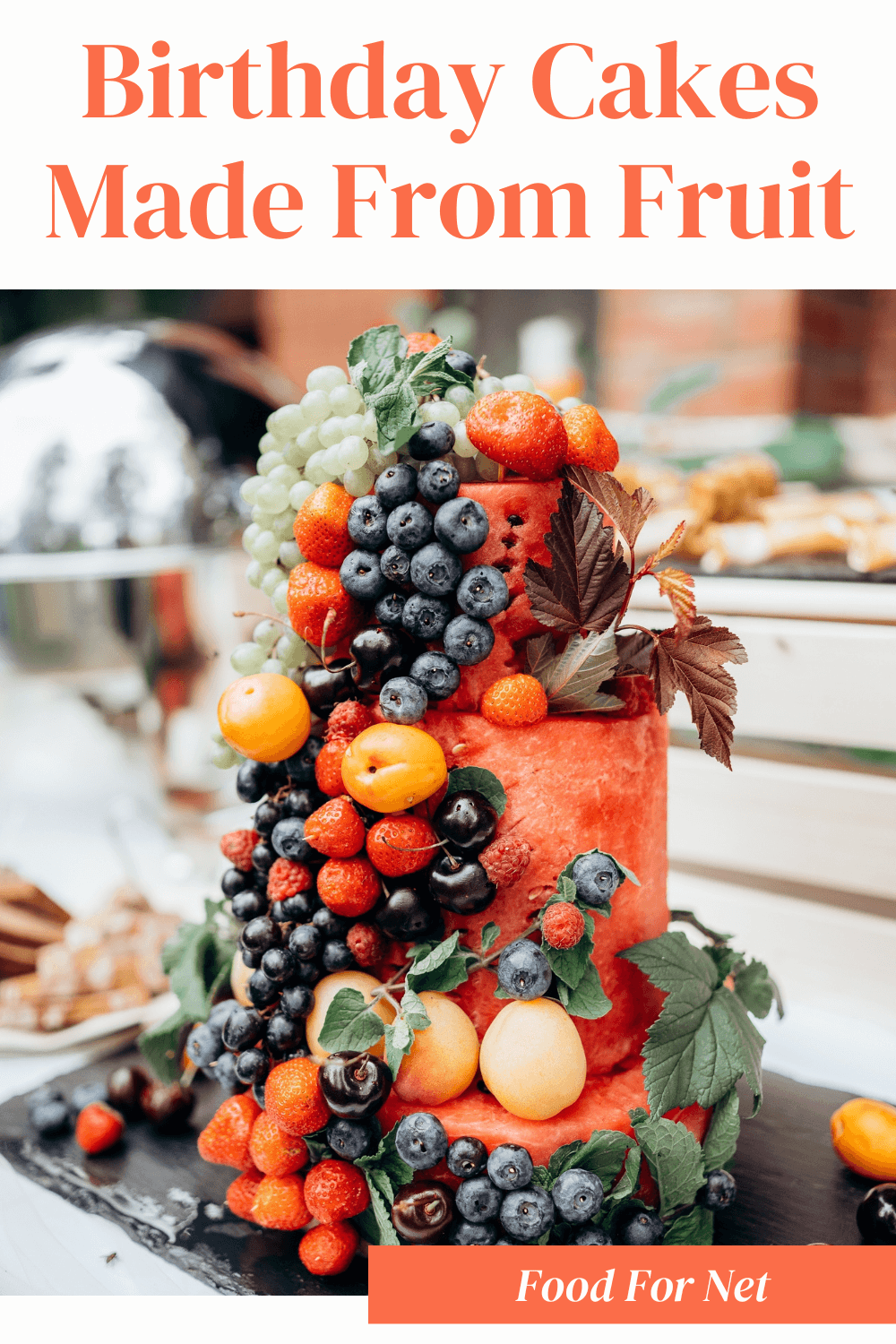 A tall birthday cake made from fruit, with watermelon as the base, then plenty of fruit stuck onto it