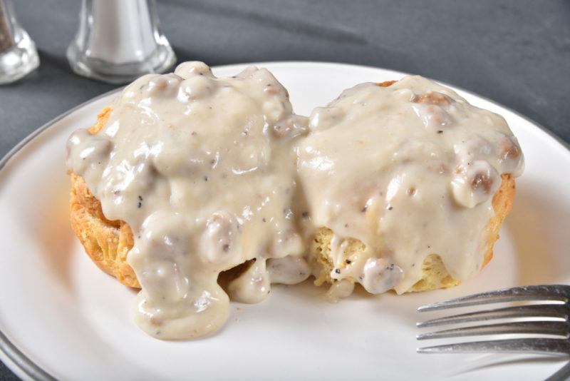 Biscuits with white sausage gravy on a white plate