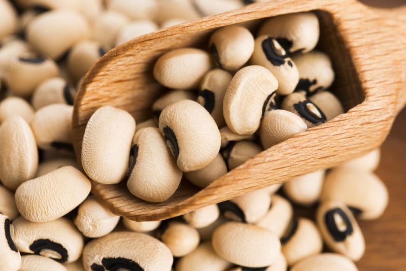 A pile of black eyed peas and a wooden scoop