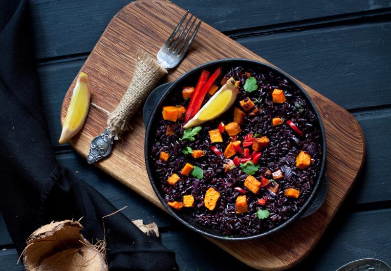 A black bowl containing black rice and other ingredients