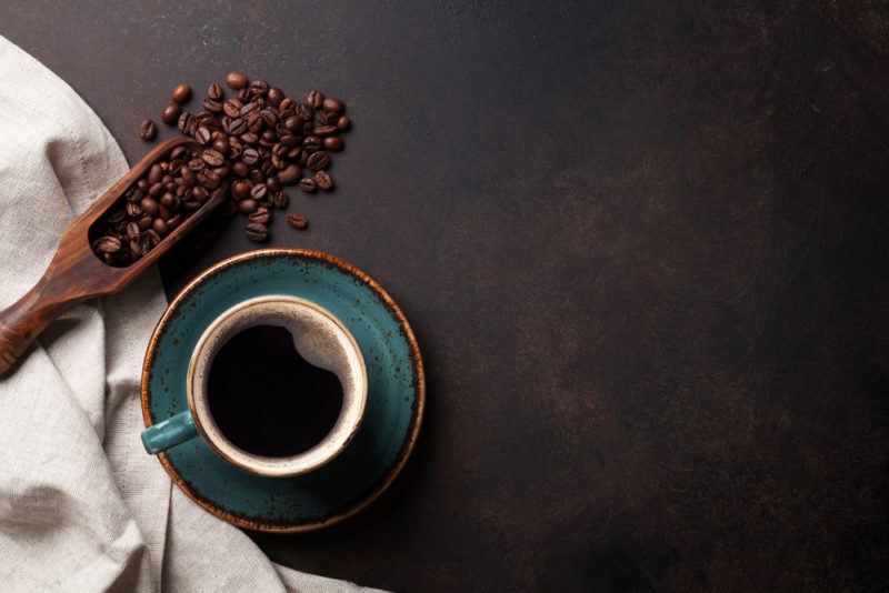 A top down image of coffee and coffee beans on a black table