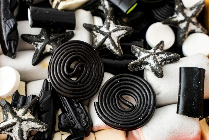 Circles of black licorice and other black licorice products next to white candies