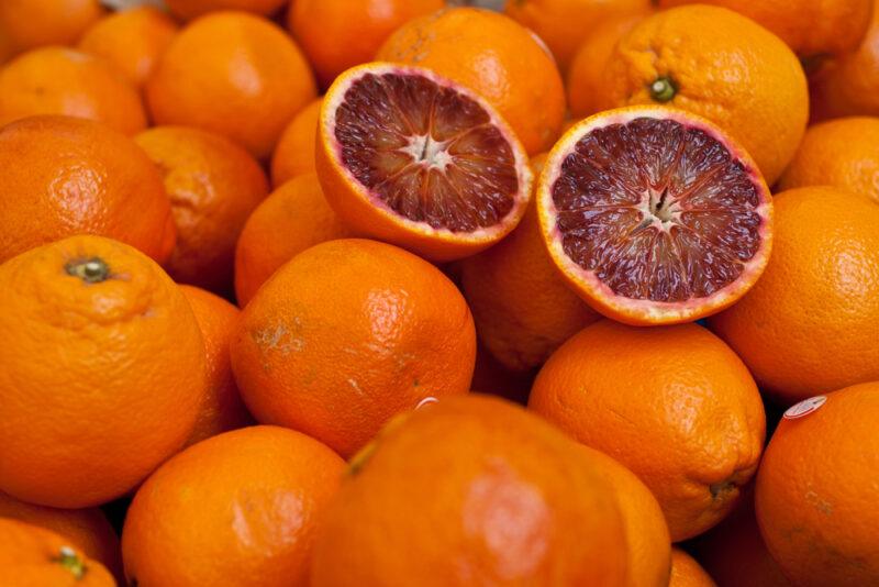 close up shot of a pile of blood oranges with one on top cut in half