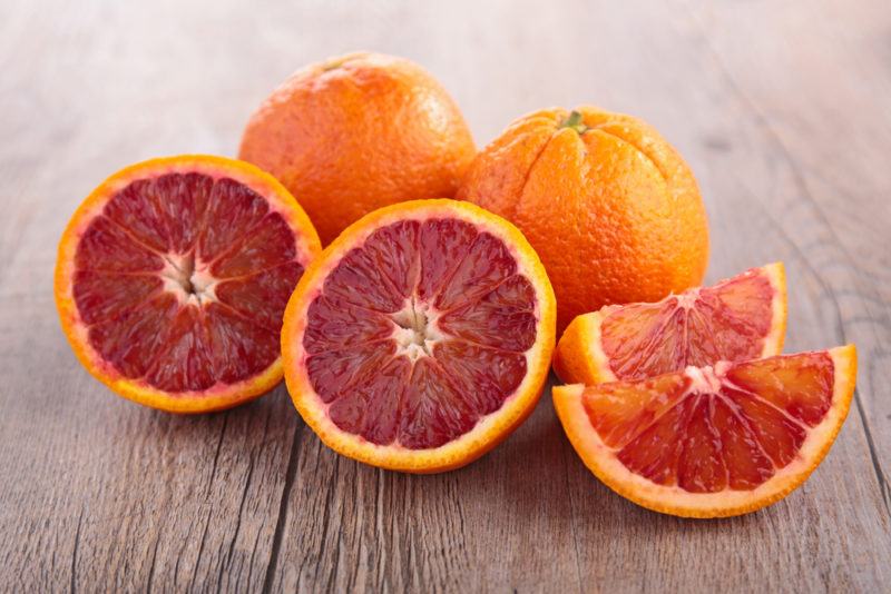 Blood oranges on a table where some have been sliced open