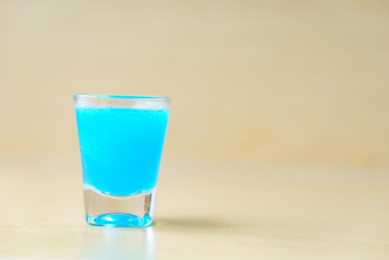 A blue kamikazi shot in a glass against a light background