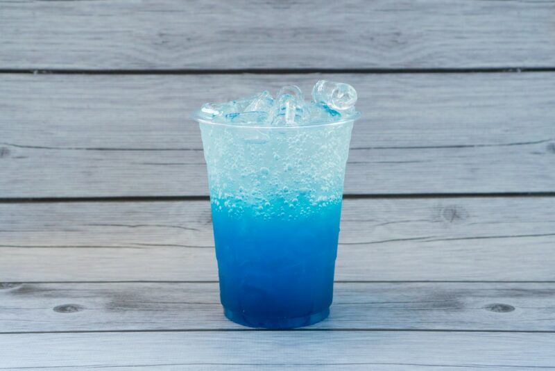 A glass containing a blue layered version of loaded tea against a wooden background