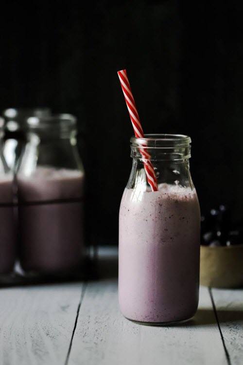 Bottles of blueberry smoothie on a wooden table against a dark background