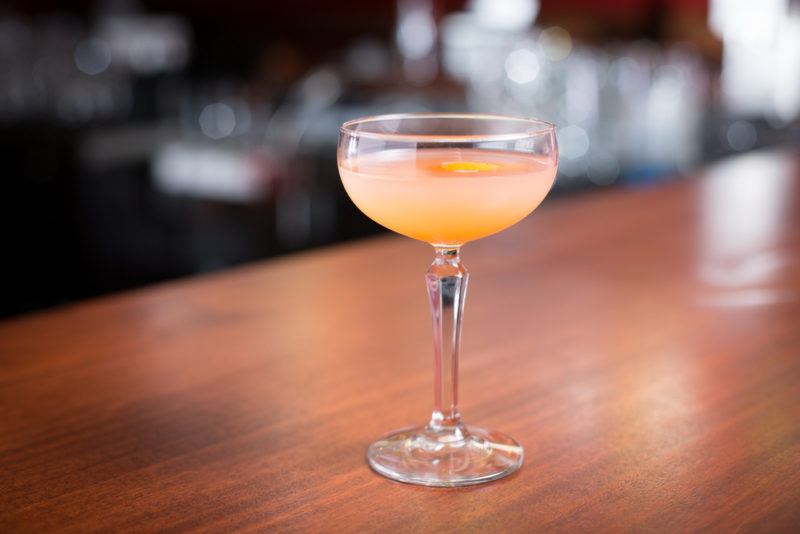 A blushing Betty cocktail in a small glass on a table