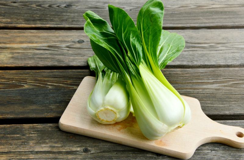 Two bok choy on a wooden board