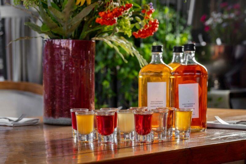 Three bottles containing different types of mead, plus shot glasses with mead