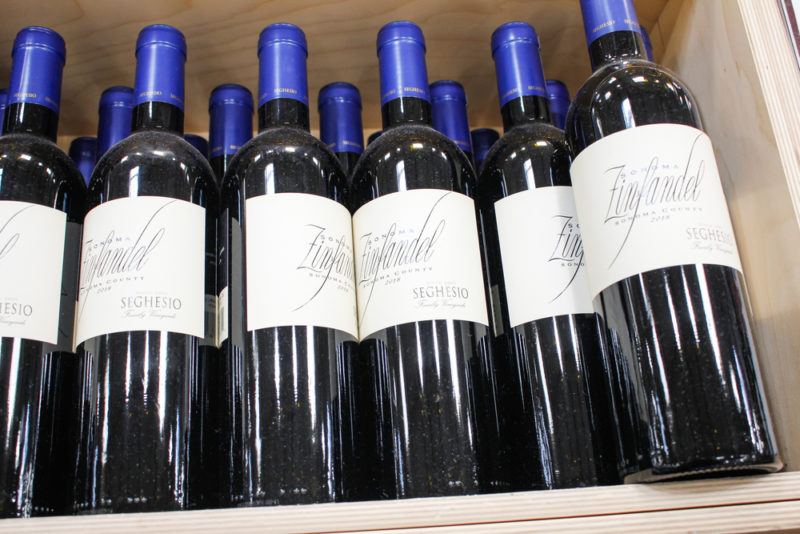 A crate of zinfandel wine in bottles with white labels and blue tops