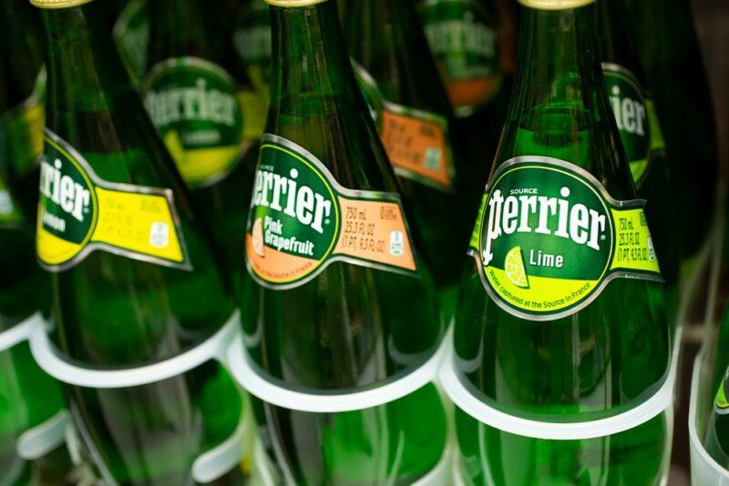 9 bottles of flavored Perrier water in the fridge in a grocery store