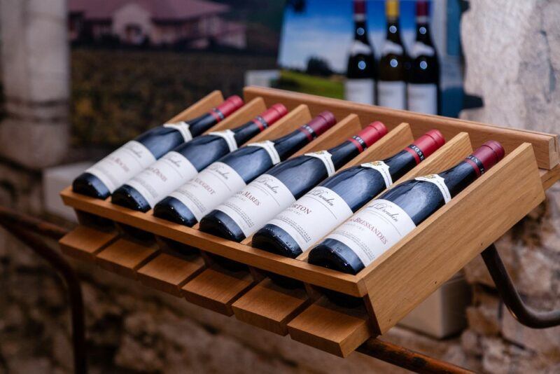 A wooden shelf with bottles of pinot noir in a wooden container