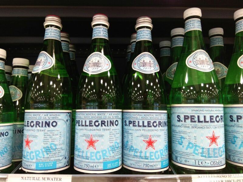 Green bottles of sparkling mineral water on the shelf in a grocery store