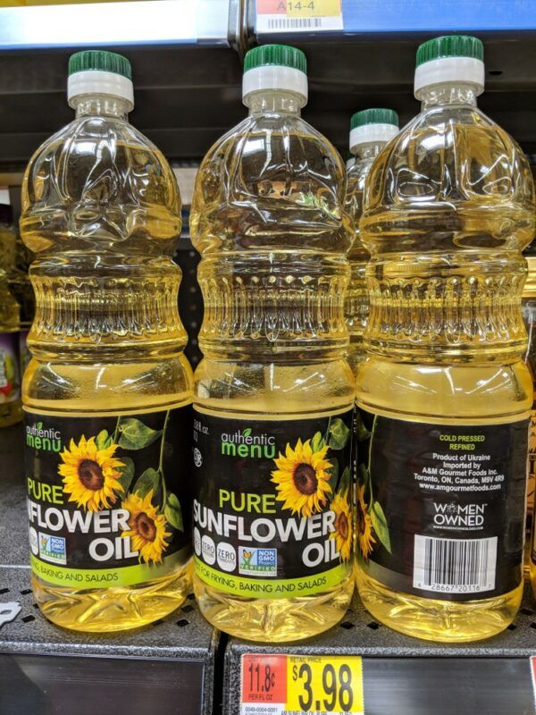 Three plastic bottles of sunflower seed oil, with some more behind them