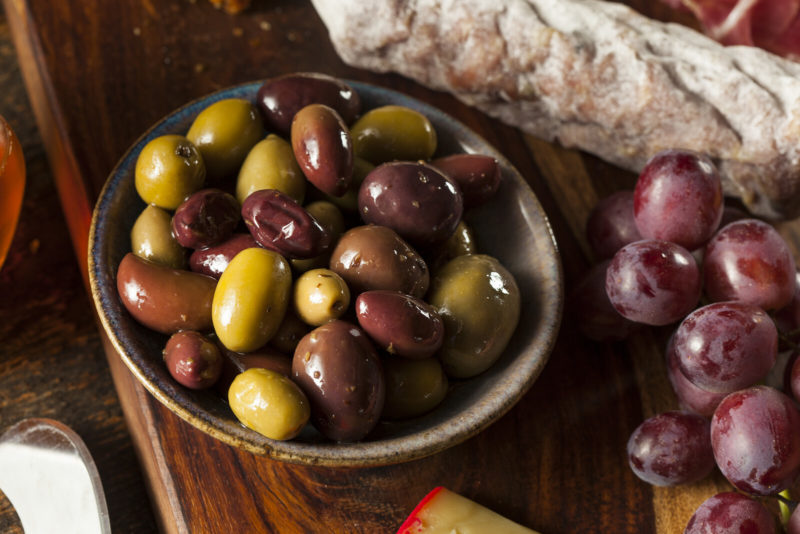 Different varieties of fresh olives in a bowl. 