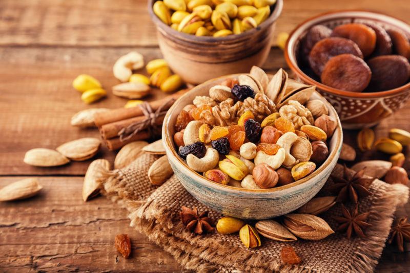 Various bowls of nuts and dried fruit, with more nuts scattered across the table