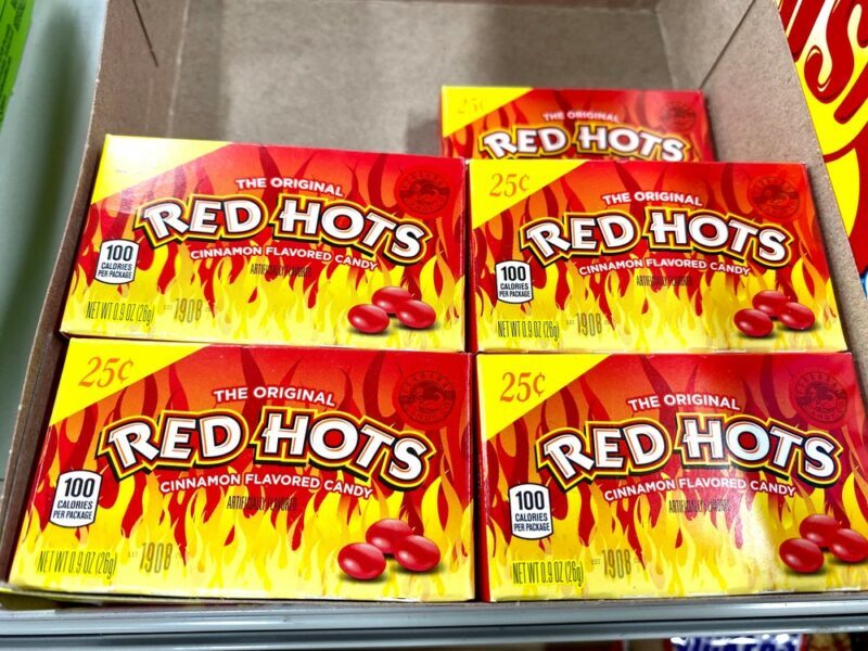 Various boxes of red hots stacked in a grocery store