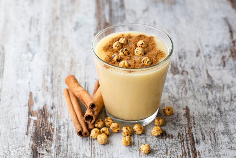 A glas of boza with cinnamon quills and chickpeas