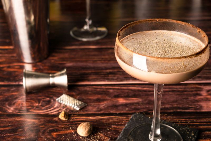 A brandy alexander cocktail on a wooden table with a jigger