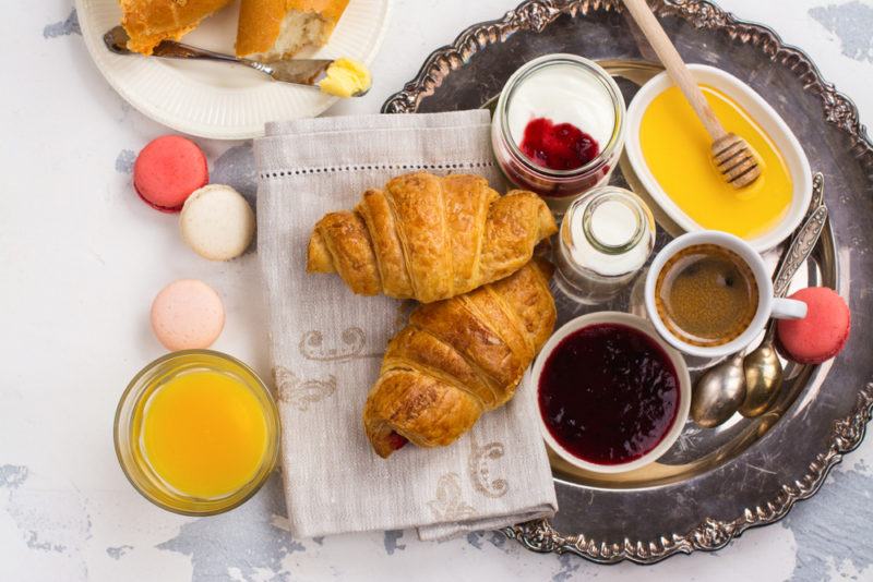 A top down images of a French breakfast, including different breads and spreads