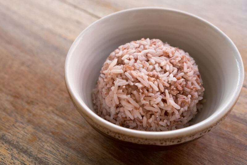 on a wooden surface is a bowl with cooked brown rice