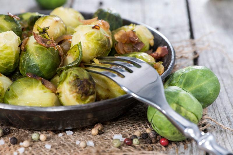 Cooked brussels sprouts in a black dish with a fork