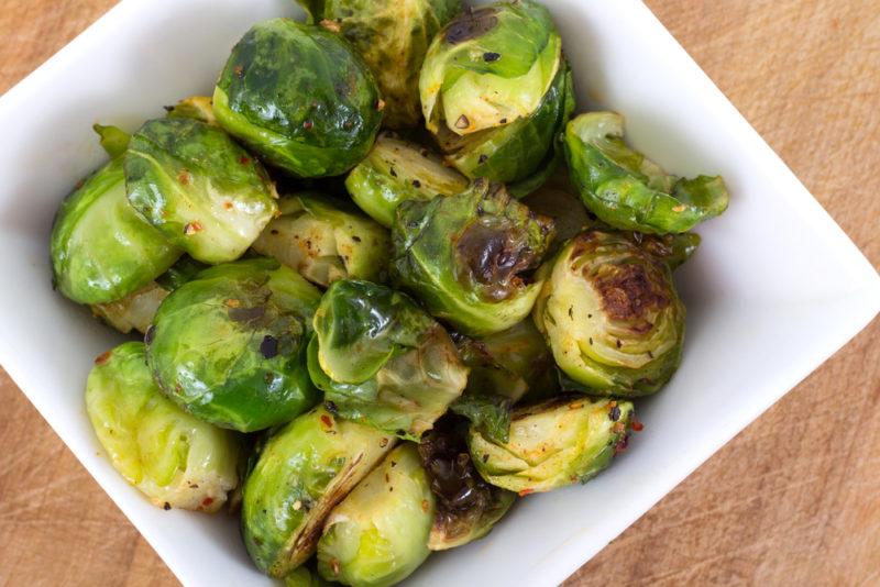 A white bowl that contains cooked Brussels sprouts