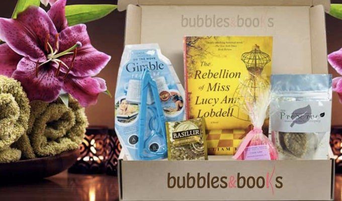 Bubbles and Books box with products for a bath, next to some rolled up towels