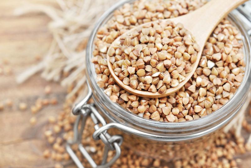 A glass jar and a spoon with buckwheat