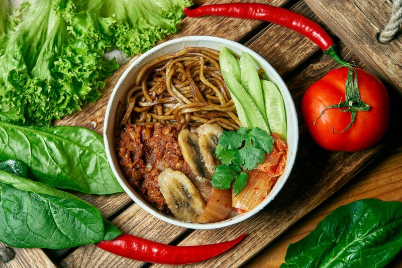 A bowl that includes buckwheat noodles, and fried bananas